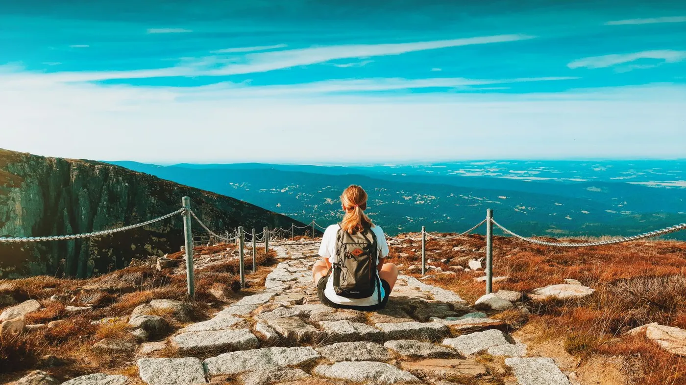 Turistka s batohem na horské stezce, ilustrace k výletu na Sněžku a do Krkonoš